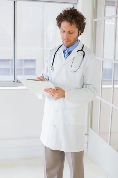 Serious male doctor writing reports in hospital — Stock Photo, Image