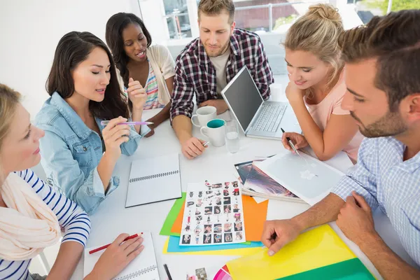 Equipo de diseño joven revisando hojas de contacto en una reunión —  Fotos de Stock