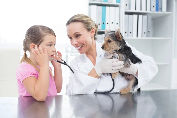 Veterinario con ragazza esaminando cucciolo — Foto Stock