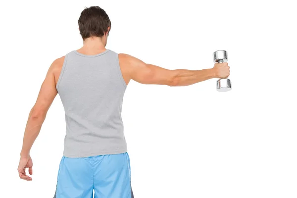 Rear view of a young man holding out dumbbell — Stock Photo, Image