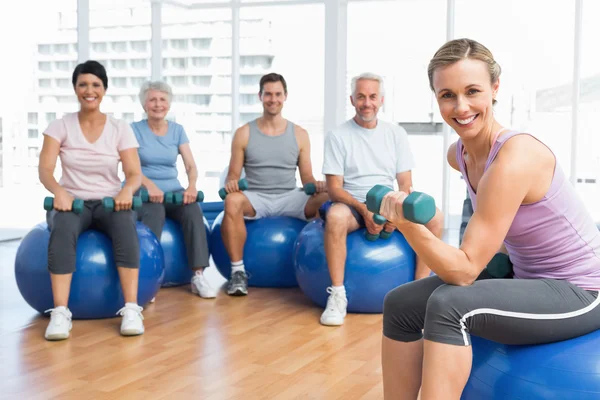 Fitness klasse met halters zittend op oefening ballen — Stockfoto