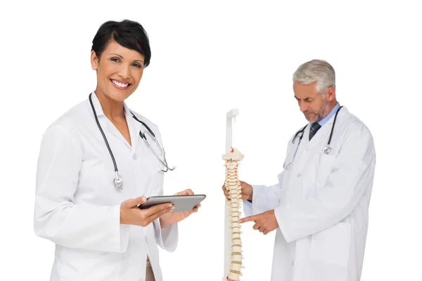 Médico sosteniendo mesa digital con colega por modelo esqueleto — Foto de Stock