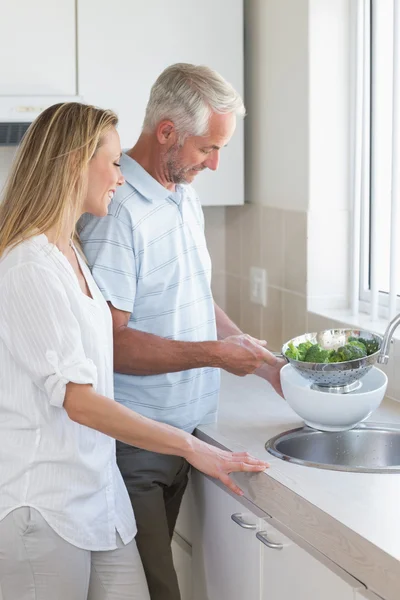 Couple rinçant les légumes à l'évier — Photo