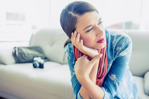 Brunette sitting on sofa looking away — Stock Photo, Image