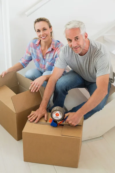 Happy couple sealing cardboard moving boxes — Stock Photo, Image