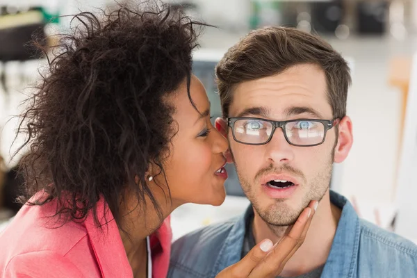 Female artist whispering into colleagues ear — Stock Photo, Image
