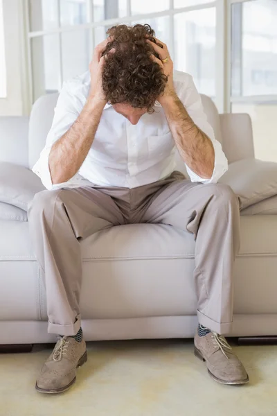 Uomo ben vestito seduto con la testa in mano a casa — Foto Stock