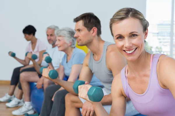 Classe con manubri seduti su palle da ginnastica in palestra — Foto Stock