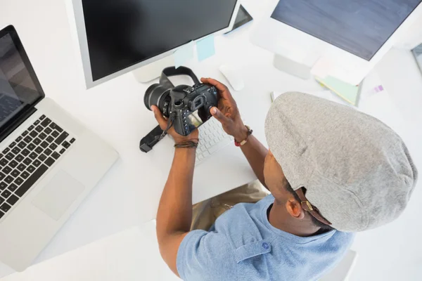 Photo editor looking at digital camera in office — Stock Photo, Image