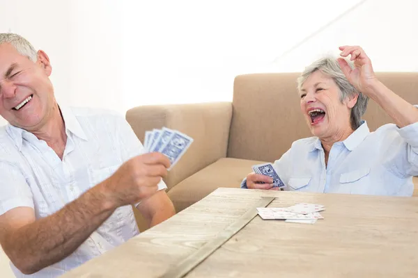 Seniorpar som sitter på gulvet og spiller kort – stockfoto