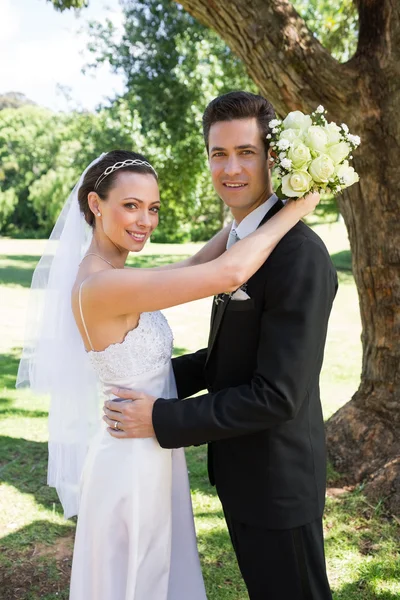 Bruden och brudgummen omfattar i trädgården — Stockfoto