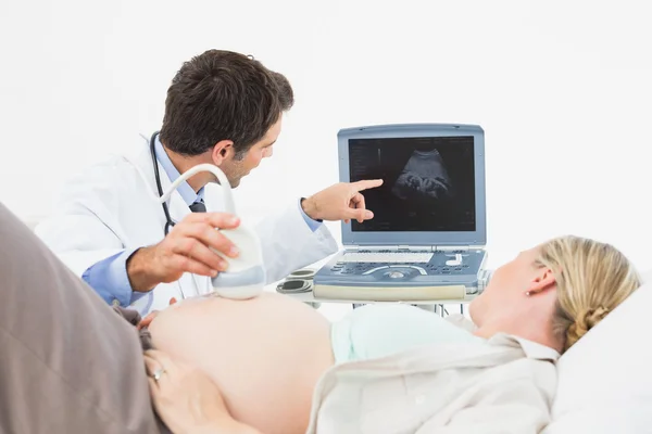 Доктор показывает женщине ее ребенка на сонаграмме — стоковое фото