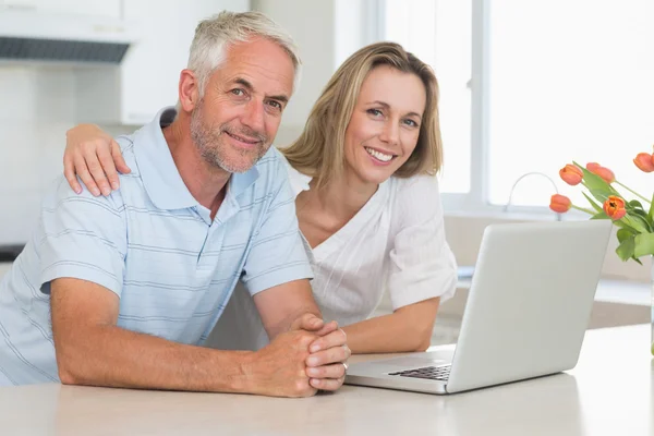 Casal alegre usando laptop juntos sorrindo para a câmera — Fotografia de Stock