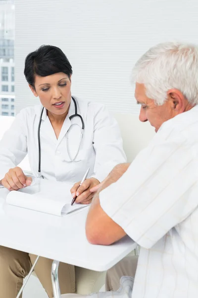 Female doctor explaining reports to senior patient — Stock Photo, Image