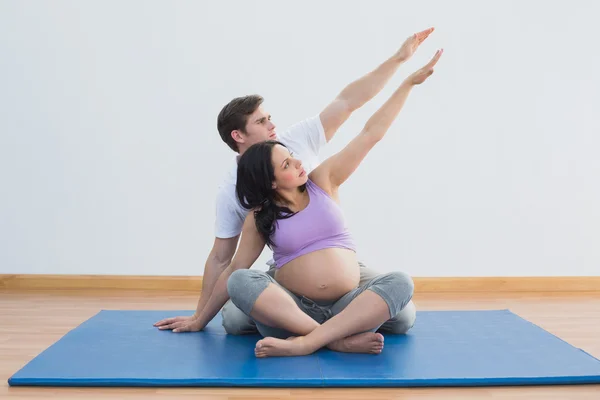Trainerin sitzt mit schwangerer Frau beim Yoga — Stockfoto
