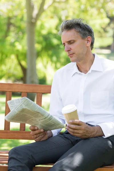 Affärsman läsa tidningen i park — Stockfoto