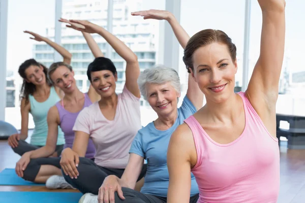 Treinador com mulheres em fila esticando as mãos na aula de ioga — Fotografia de Stock