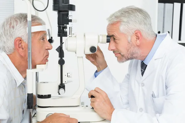 Optometrista fazendo teste de visão para paciente sênior — Fotografia de Stock