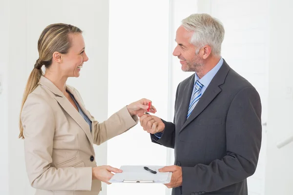 Smiling estate agent giving house key to happy customer — Stock Photo, Image