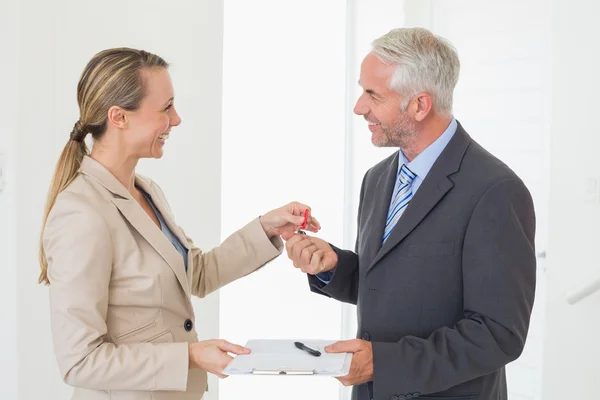 Sorrindo agente imobiliário dando a chave da casa para o cliente feliz — Fotografia de Stock