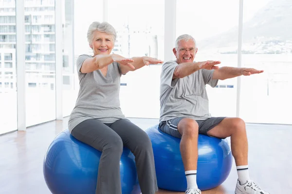 Casal sênior fazendo exercícios de alongamento em bolas de fitness — Fotografia de Stock