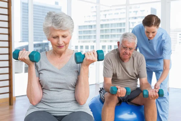 Női terapeuta segíti a súlyzó idősebb pár — Stock Fotó