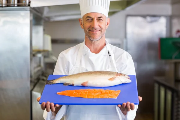 Confidence chef holding tray of raw fish in kitchen — Stock Photo, Image