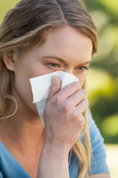 Woman blowing nose with tissue paper at park — Stock Photo, Image