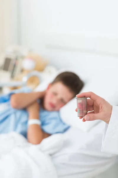 Docteur tenant bouteille de pilule avec garçon en salle — Photo