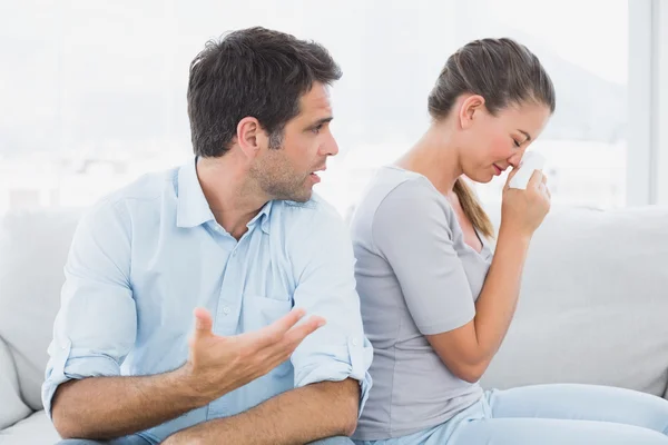 Homem implorando com seu parceiro chorando no sofá — Fotografia de Stock