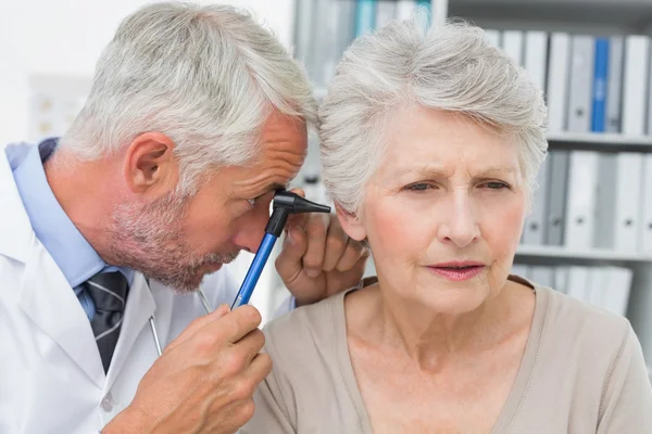 Close-up de um médico masculino examinando a orelha do paciente sênior — Fotografia de Stock