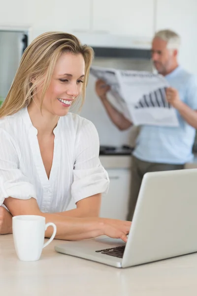 Leende kvinna använder laptop med partner står med papper — Stockfoto