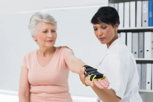 Női orvos rögzítése csukló zárójel a kéz idősebb betegek — Stock Fotó