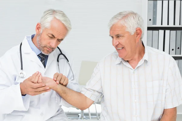 Врач-мужчина измеряет пульс пожилых пациентов — стоковое фото