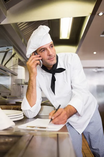 Cook writing on clipboard in kitchen — Stock Photo, Image