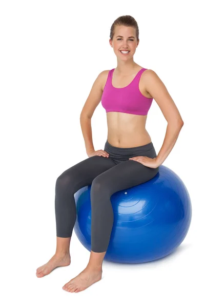 Retrato de una mujer en forma sentada en una pelota de ejercicio —  Fotos de Stock