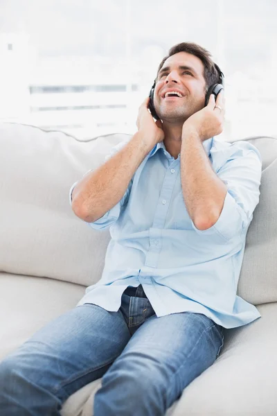 Homem feliz sentado no sofá ouvindo música — Fotografia de Stock