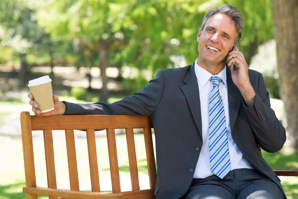 Businessman with disposable cup answering cellphone — Stock Photo, Image