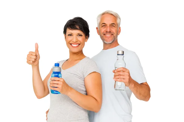 Подходящая пара с бутылками воды, жестикулирующими большими пальцами вверх — стоковое фото