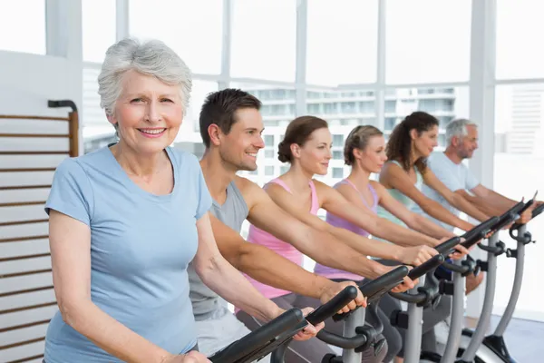 Gente feliz haciendo ejercicio en la clase de spinning —  Fotos de Stock