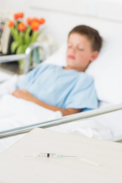 Jeringa sobre la mesa con niño en la sala del hospital —  Fotos de Stock