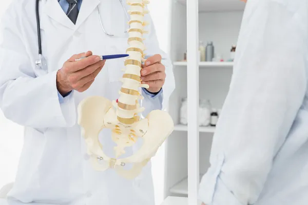 Sezione centrale del medico che spiega la colonna vertebrale al paziente — Foto Stock