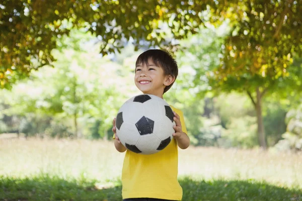 Zadowolony ładny chłopczyk z piłki nożnej w parku — Zdjęcie stockowe