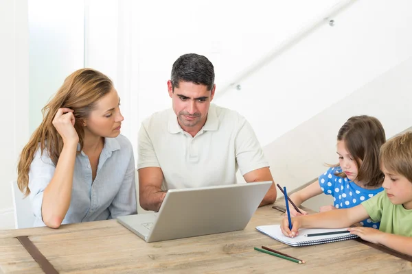 Föräldrar använder laptop medan barn coloring — Stockfoto