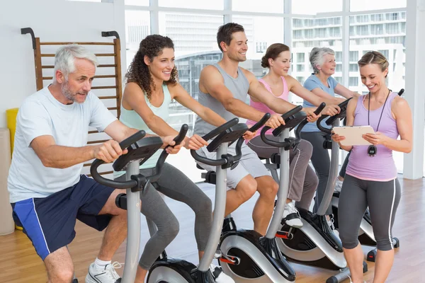 Trainer oltre alle persone che si allenano a lezione di spinning — Foto Stock