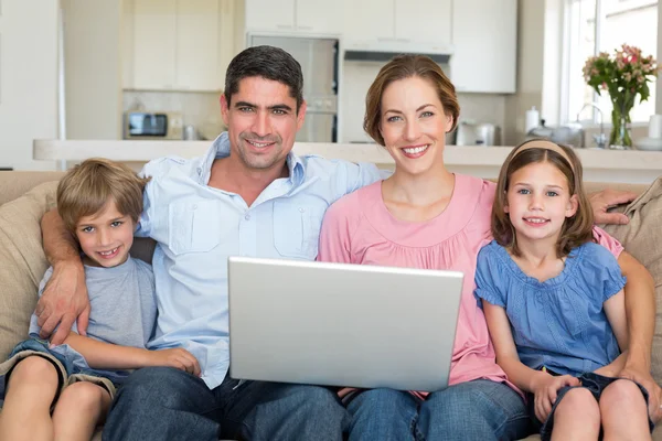 Familia con portátil sentado en el sofá — Foto de Stock