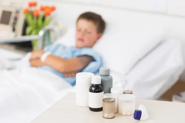 Medicines on table with boy in bed — Stock Photo, Image