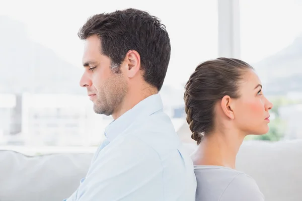 Unhappy couple sitting back to back on the couch — Stock Photo, Image