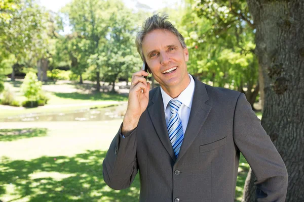 Businessman answering smart phone — Stock Photo, Image