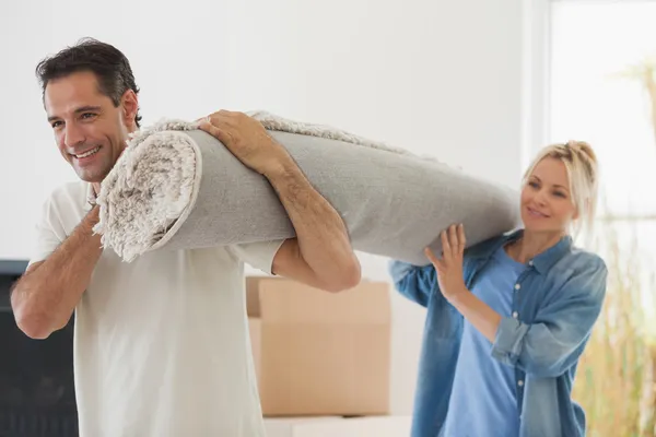 Couple carrying rolled rug — Stock Photo, Image